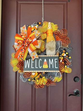 image of large Halloween Candy Corn Wreath. Candy Corn gnome in yellow, orange and white. Black and White Welcome Sign with Candy corn design. Large bow with long tails. 